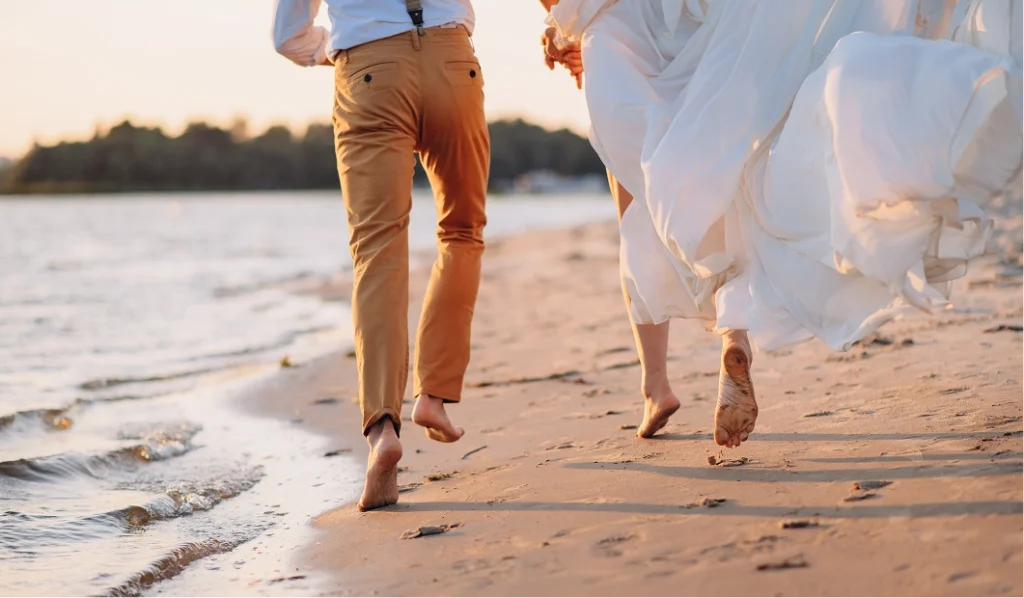 Couple running on beach at wedding
